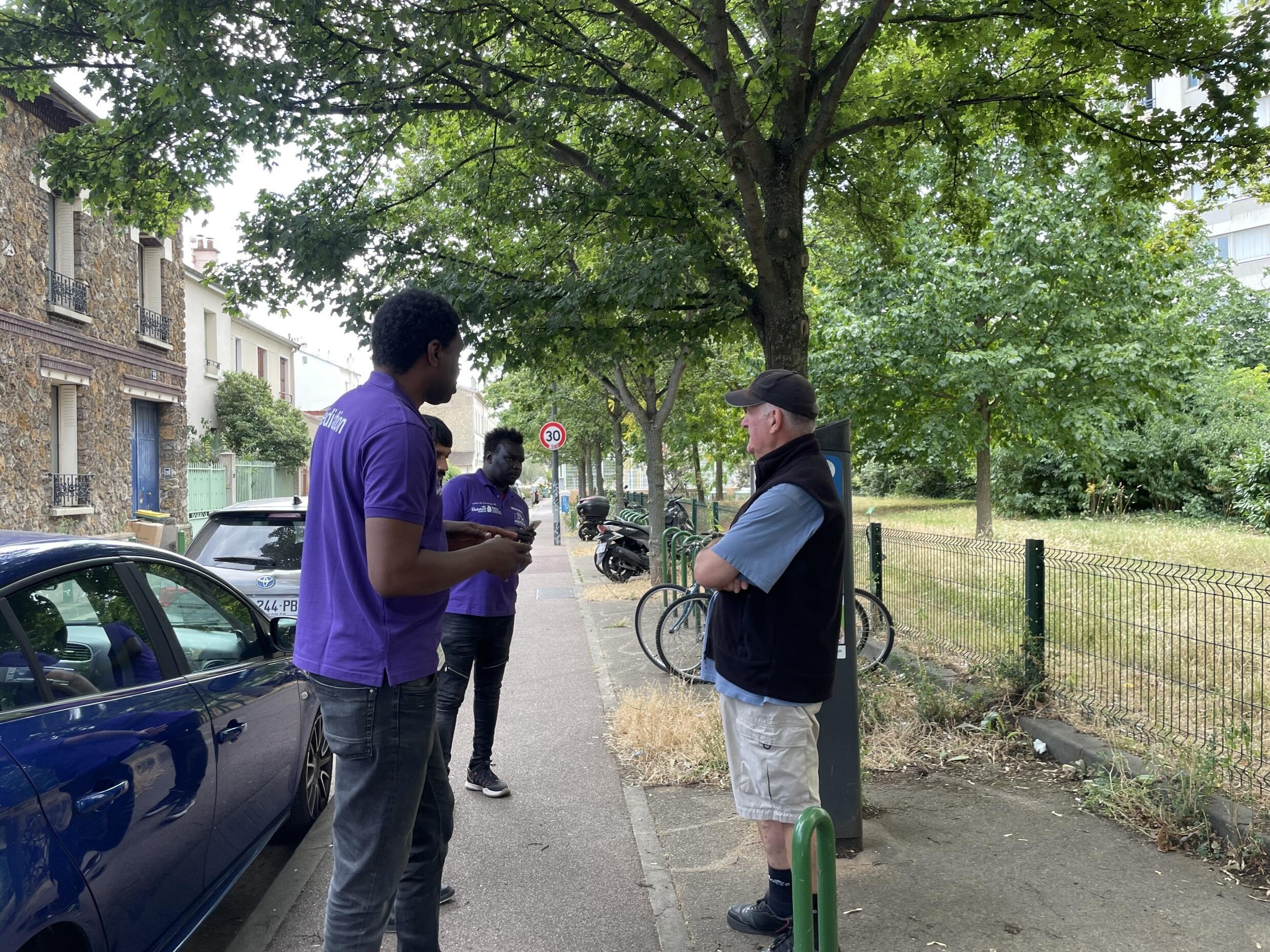 Samba Baye and Baba Diop, social workers in Malakoff, talk to a local resident a few hours before the Bastille Day festivities on July 13, 2023.