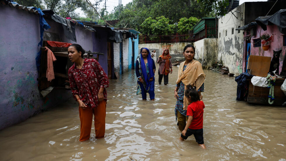 In this photo taken in New Delhi, India on July 14, 2023, people wait in a flooded alley after a rise in the waters of the Yamuna river due to heavy monsoon rains. Rescuers were searching on July 20 for survivors of a deadly landslide that occurred after heavy rainfall in Irshalwadi, a hamlet in the western state of Maharashtra.
